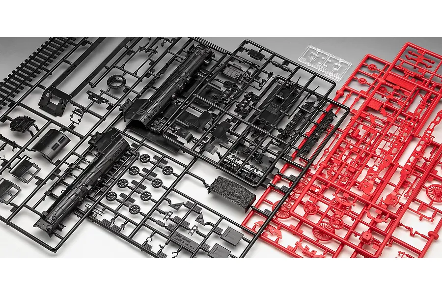 Plastic model kit sprues for a Revell 1/87 scale train locomotive, featuring black and red molded parts on a grey background.