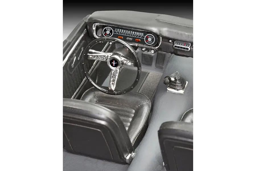 Close-up of the detailed interior of a 1/24 scale 1965 Ford Mustang model car, showing the dashboard, steering wheel, and front bucket seats.