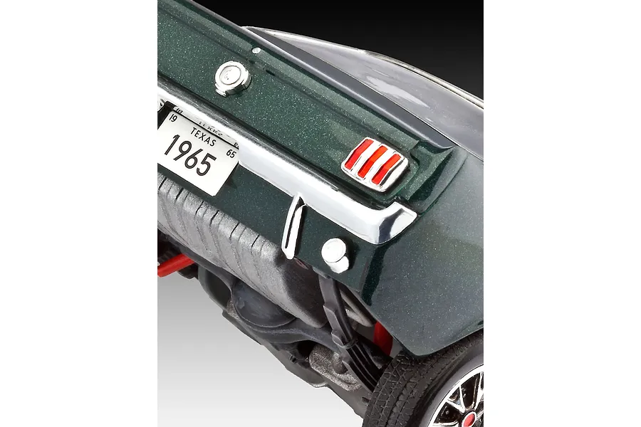 Close-up of the rear end of a dark green 1965 Ford Mustang model car, showing the taillight, Texas license plate, and rear chassis details.