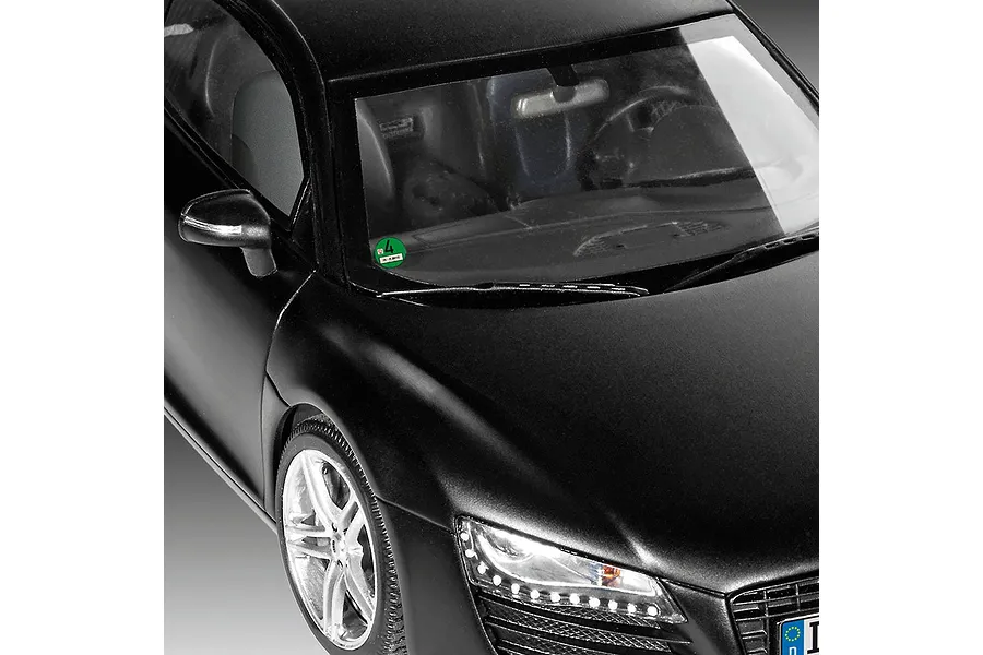 Close-up of a matte black Audi R8 model car showing the windshield, side mirror, and front headlight detail.