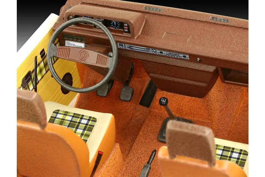 Close-up of the detailed interior of a 1/24 scale Revell VW T3 Bus model, showing the dashboard, steering wheel, seats with plaid fabric, and gear stick.
