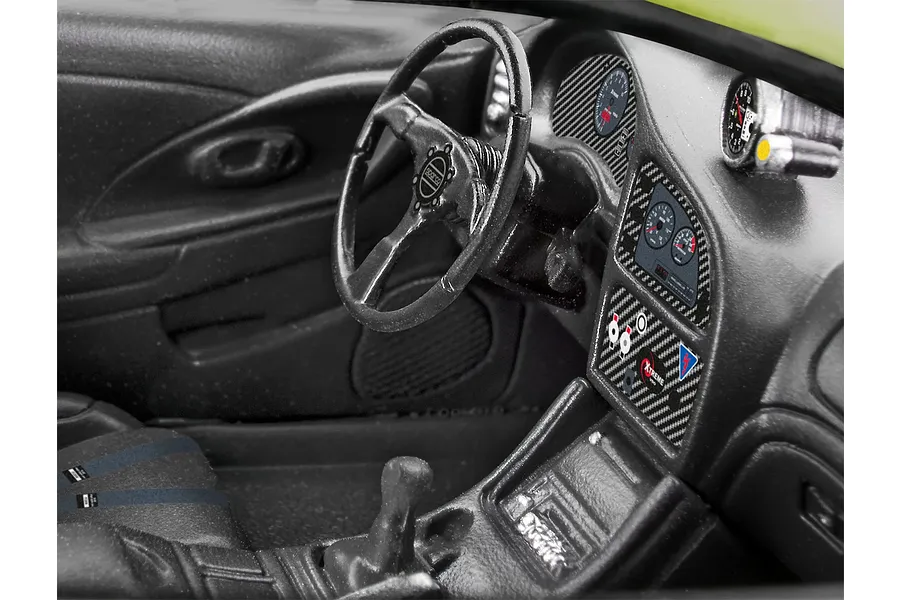 Close-up of the detailed black interior of a 1/25 scale model Mitsubishi Eclipse, featuring a steering wheel, dashboard gauges, and center console.