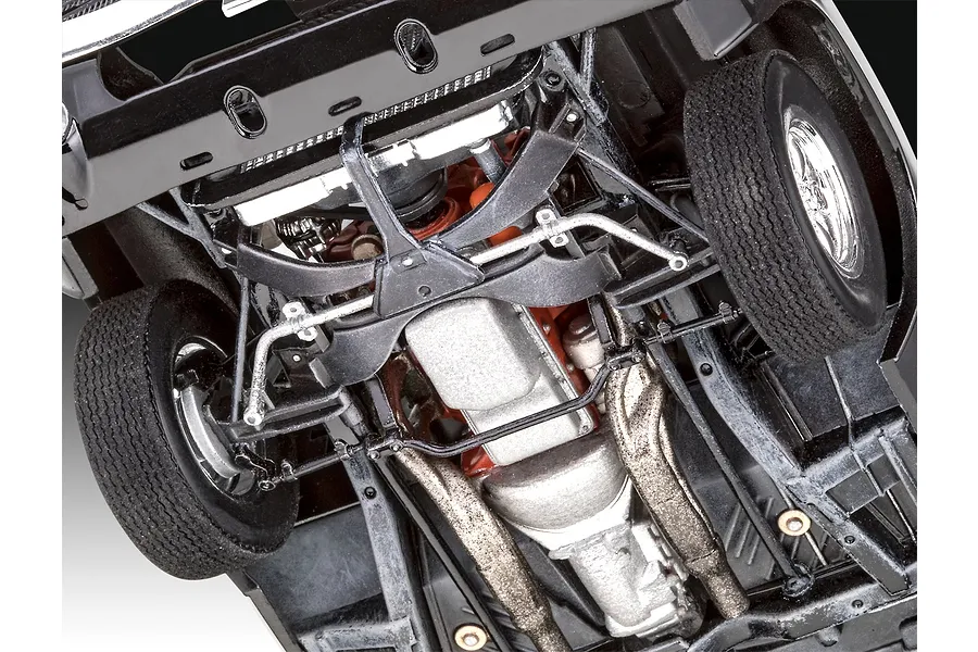 Underside view of a 1/25 scale plastic model 1970 Dodge Charger showing the chassis, engine block, transmission, and front suspension details.