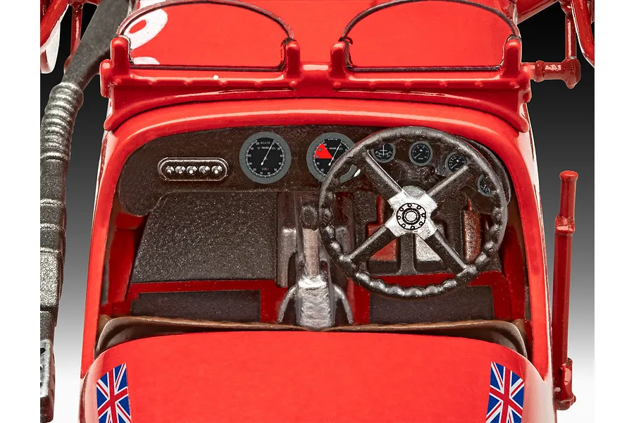 Close-up of the detailed interior cockpit of a red Revell 1/32 scale Aston Martin Ulster model car, featuring a steering wheel, dashboard gauges, and Union Jack decals.