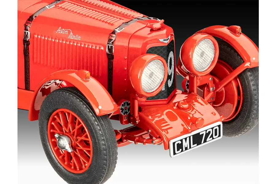 Close-up of a red 1/32 scale Aston Martin Ulster model car showing the front grille, headlights, and wire-spoke wheels.