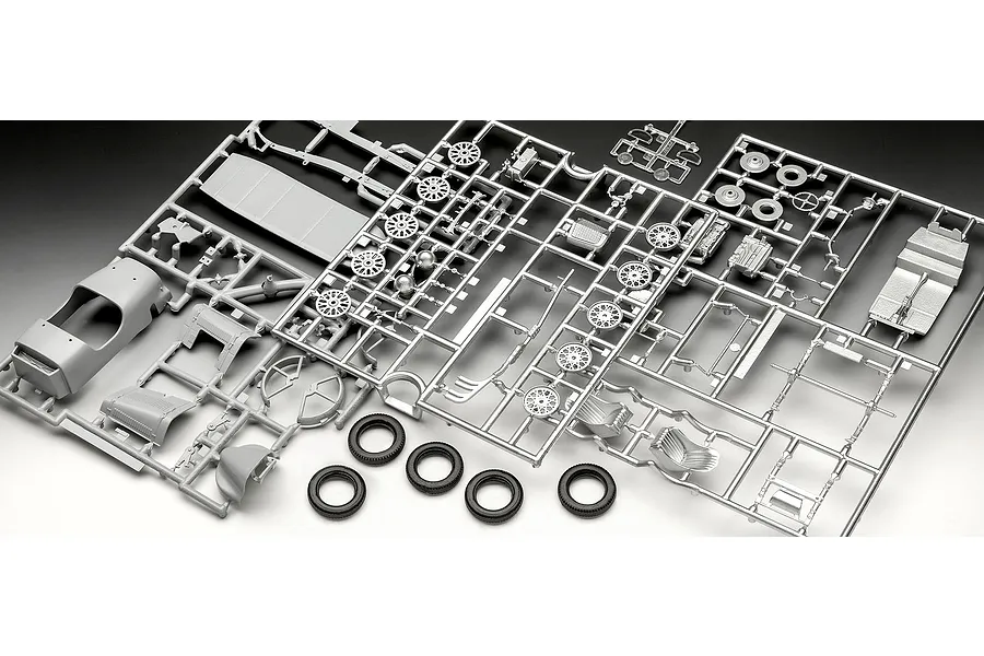 Plastic model kit parts for an Aston Martin Ulster, including grey sprues with car body panels, engine components, and four black rubber tires.