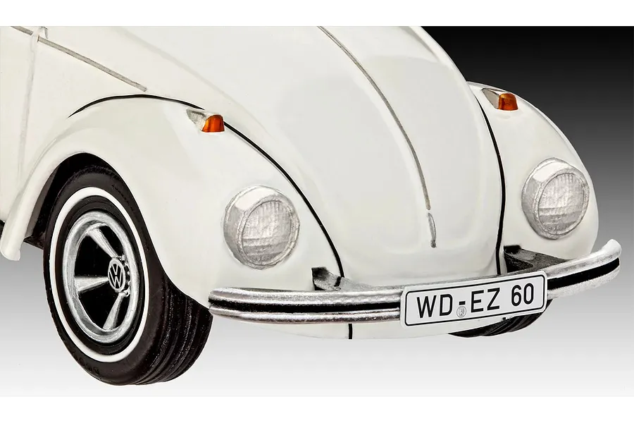 Close-up of the front end of a white Revell 1/32 scale VW Beetle model car, showing the bumper, headlight, and license plate.