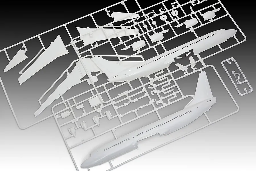 White plastic model aircraft kit sprues for a Boeing 737-800, including fuselage halves, wings, and engine parts on a grey background.