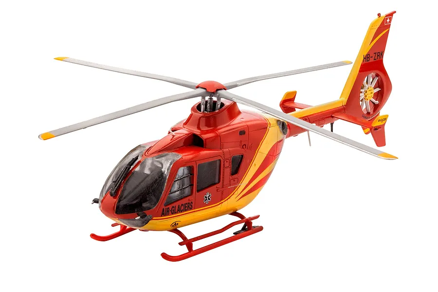 A completed 1/72 scale plastic model of an Airbus EC135 helicopter in Air-Glaciers livery, featuring red and yellow paint with medical markings.