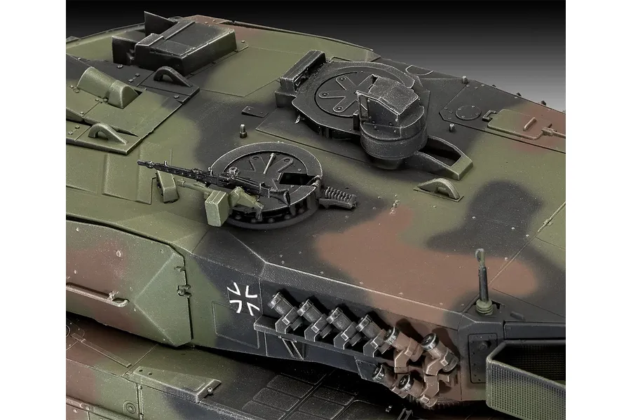 Close-up of the turret top of a painted 1/35 scale Leopard 2 A6 model tank showing camouflage paint, hatches, and a mounted machine gun.
