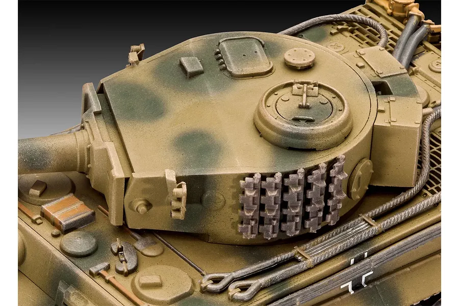 Close-up of a 1/72 scale plastic model Tiger tank turret with camouflage paint and spare track links mounted on the side.