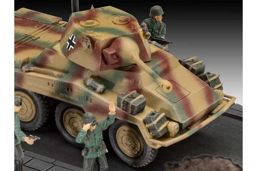 A 1/76 scale plastic model of a German Sd.Kfz. 234-2 Puma armored car with camouflage paint, featuring two painted soldier figures on a display base.