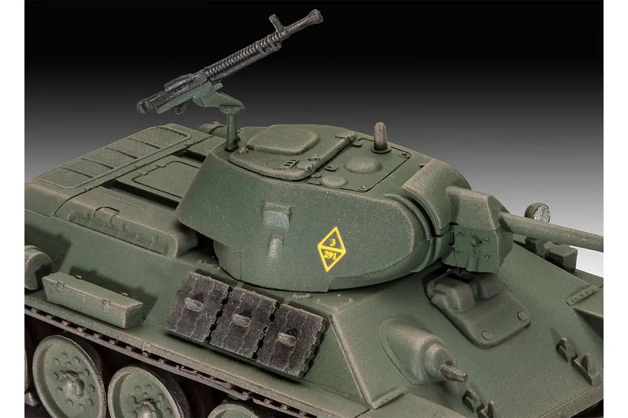 Close-up of a 1/76 scale plastic model T-34-76 tank, showing the turret, machine gun, and green camouflage paint.
