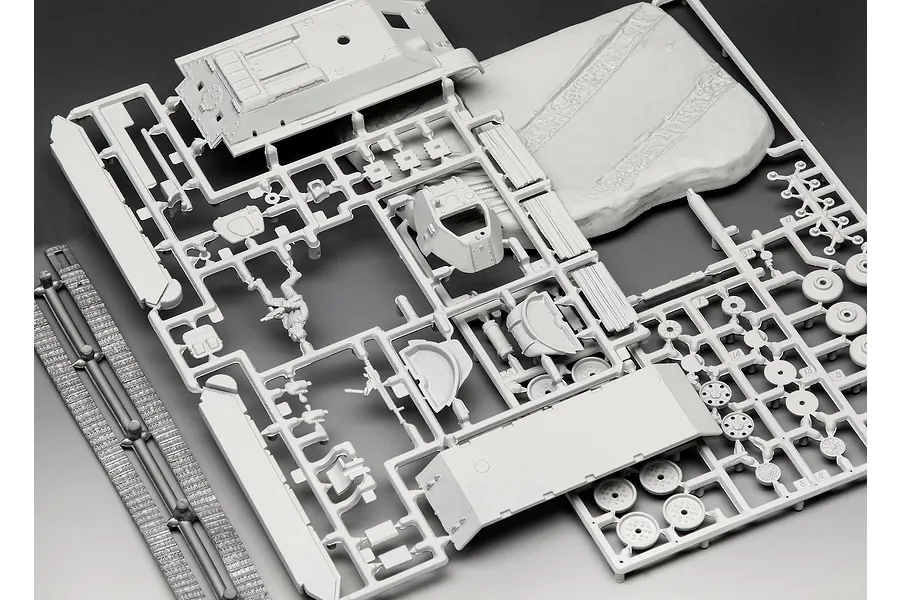 Unassembled grey plastic model kit parts for a T-34-76 tank on sprues, including hull, turret, tracks, and a small terrain base.