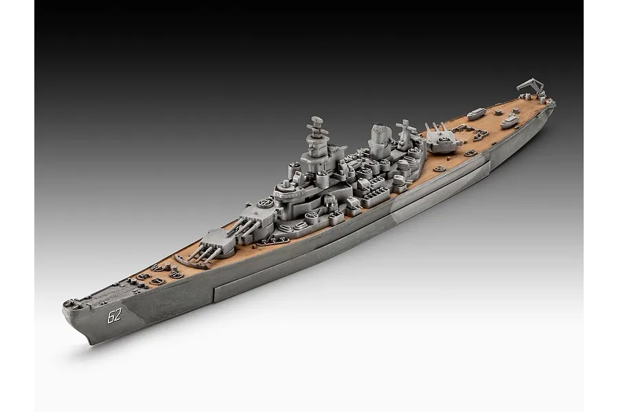 A high-angle studio shot of a 1/1200 scale Revell USS New Jersey battleship model, showing the grey hull and tan deck with the number 62 on the bow.
