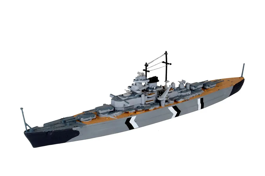 A fully assembled and painted 1/1200 scale plastic model of the German battleship Bismarck, featuring grey, black, and tan camouflage patterns.