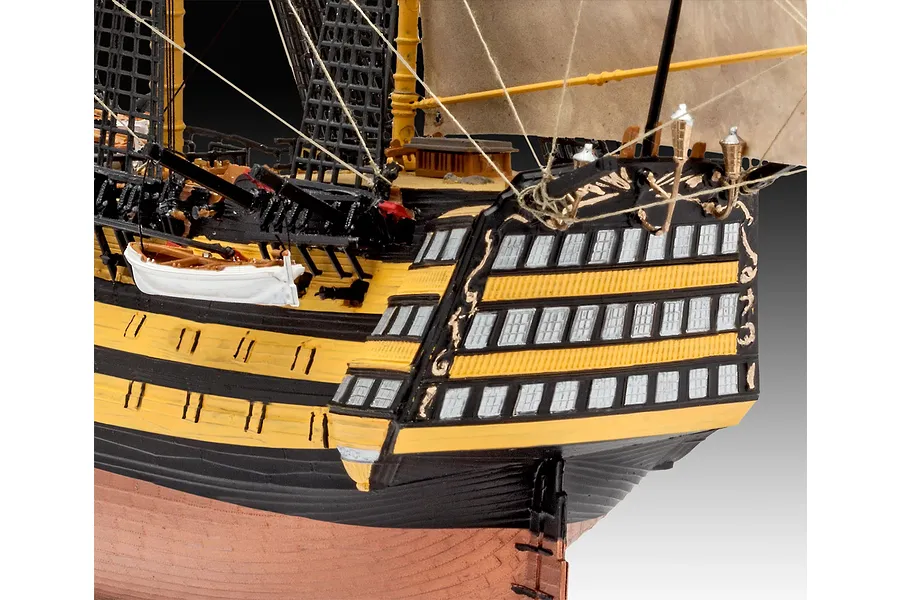 Close-up of the stern section of a detailed HMS Victory plastic model ship, showing black and yellow hull, rigging, and small lifeboats.