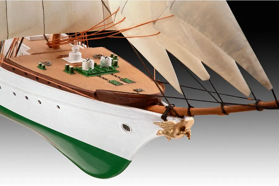 Close-up of the bow section of a Gorch Fock model ship showing the white hull, green bottom, wooden deck, and rigging.