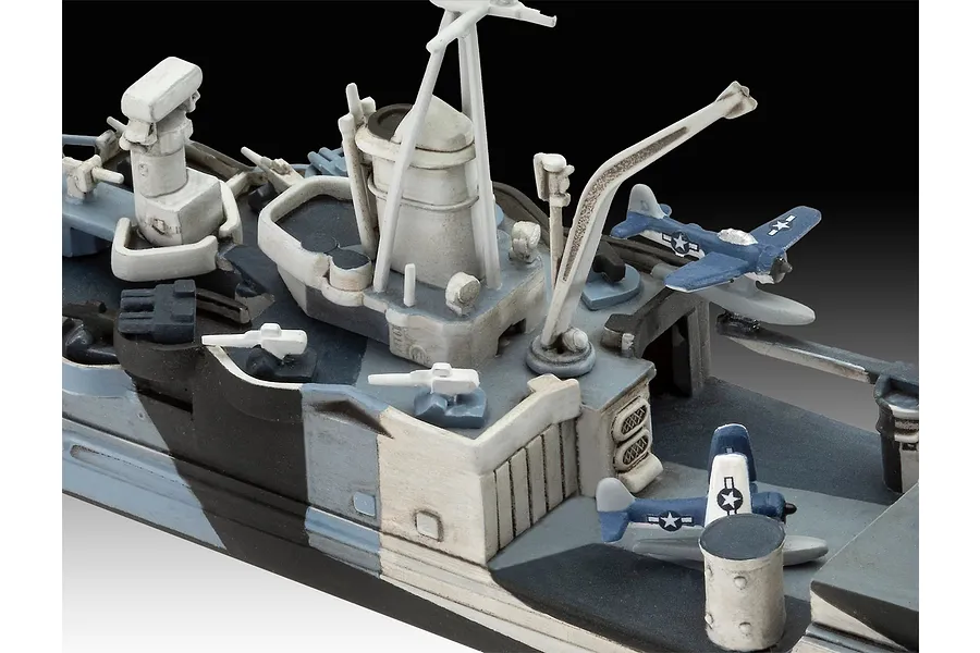 Close-up of a 1/700 scale model ship deck featuring a crane, radar mast, and two small floatplanes with US Navy markings.