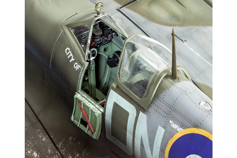 Close-up of a 1/32 scale plastic model Spitfire cockpit with open canopy and detailed interior.