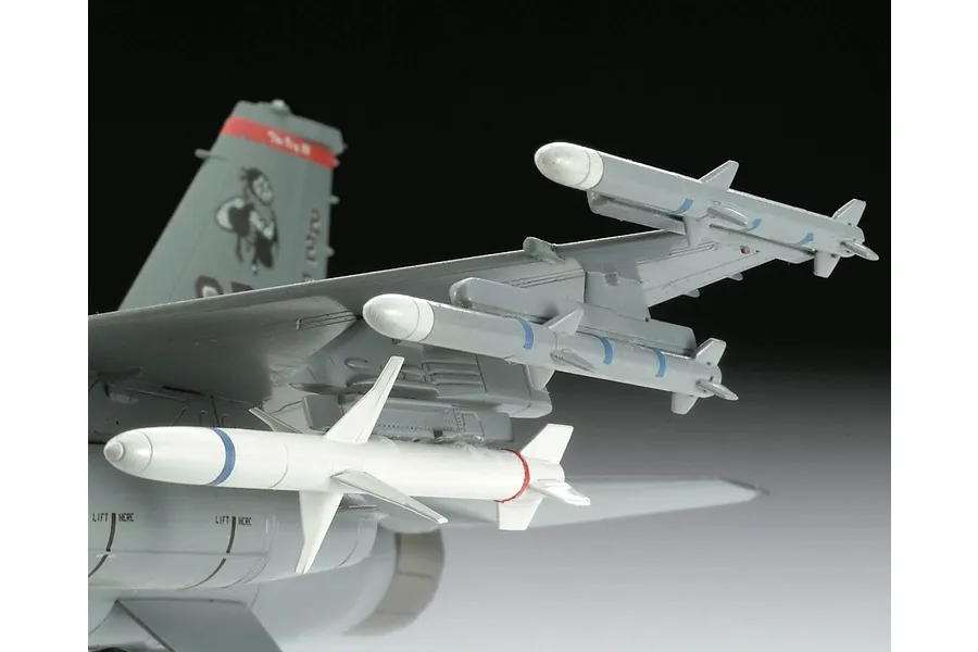 Close-up of a plastic model F-16 fighter jet wing showing mounted missiles and tail section details.