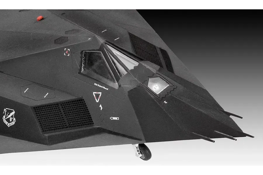 Close-up of the cockpit and nose section of a black F-117 Nighthawk plastic model aircraft.