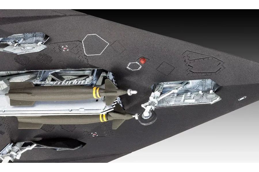 Close-up of the underside of a plastic model F-117 Nighthawk showing open bomb bay doors with two missiles and landing gear.