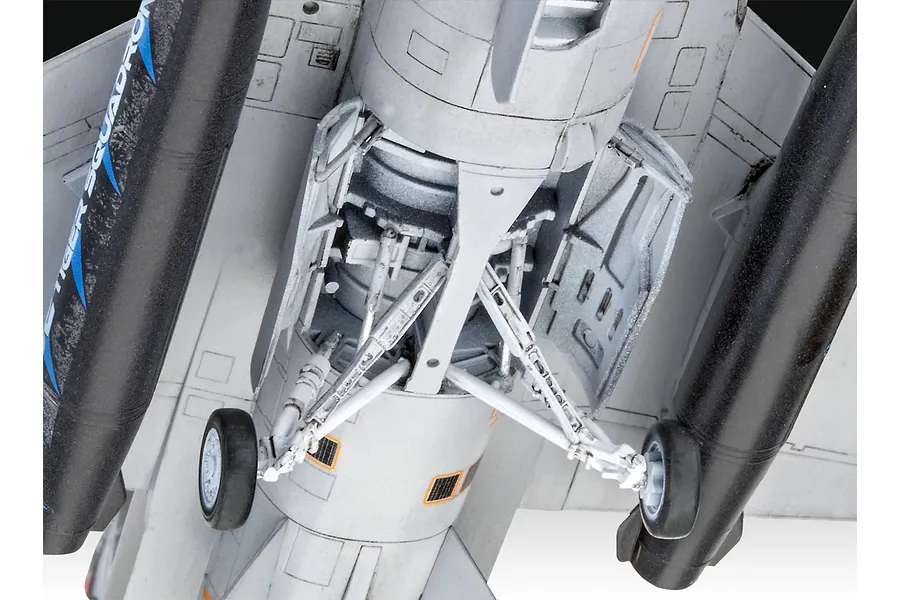 Close-up view of the underside of a 1/72 scale plastic model F-16 fighter jet, showing the landing gear assembly and external fuel tanks.