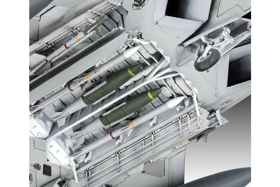 Close-up of the open weapons bay of a 1/72 scale F-22A Raptor model kit, showing detailed missiles and bombs mounted inside.