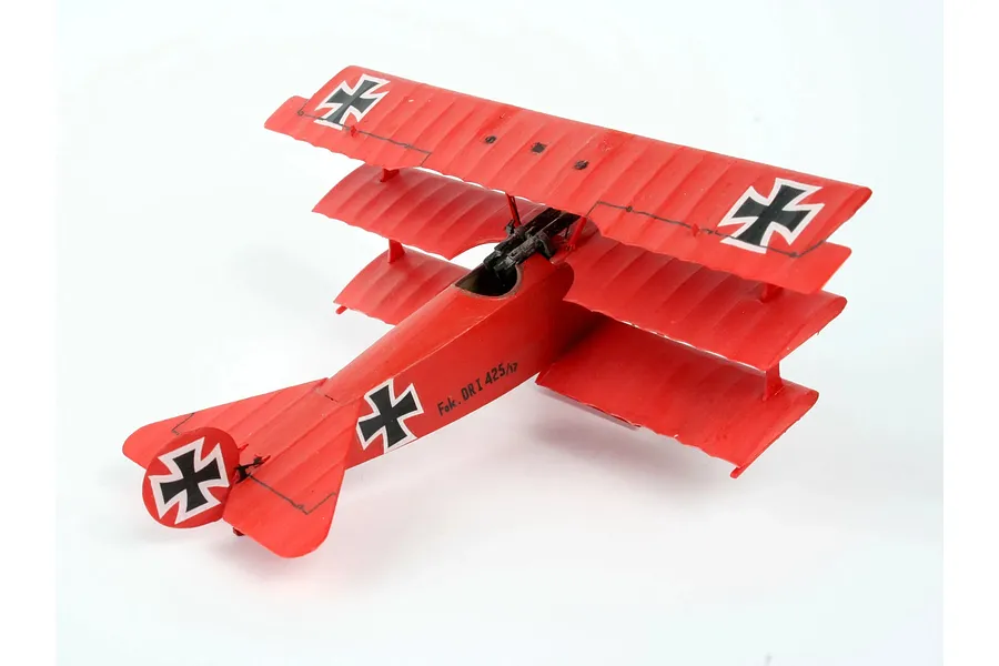 A fully assembled and painted red Fokker DR.1 triplane model aircraft on a white background.
