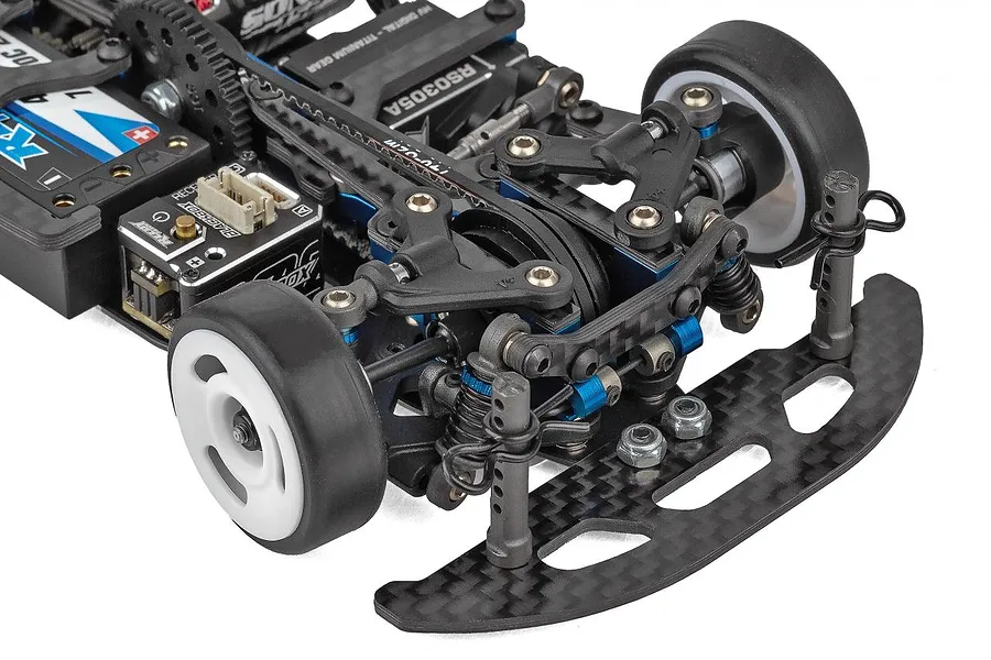Close-up of the front chassis assembly of a Team Associated TC28 1/28 scale RC car, showing carbon fiber bumper, suspension, and electronics.