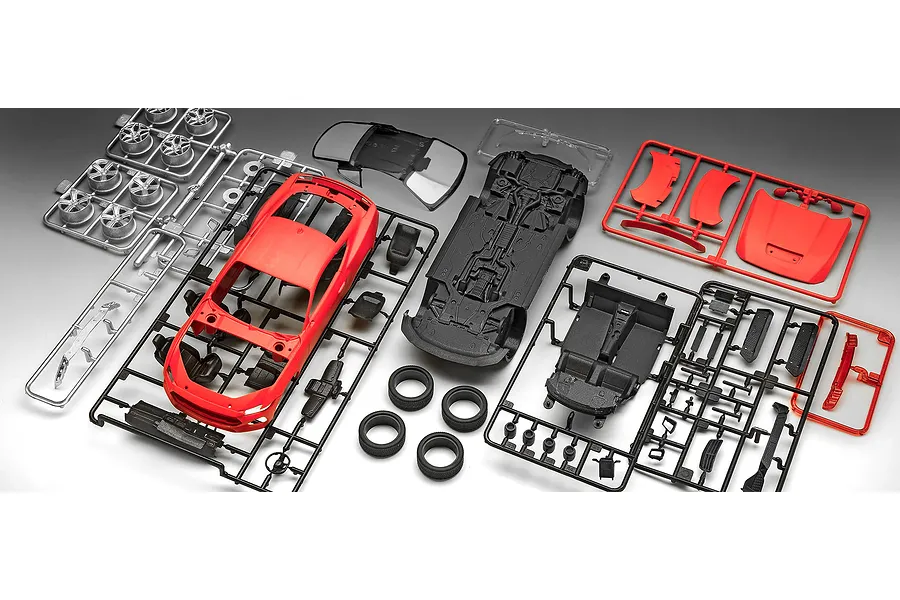 Unassembled plastic model kit parts for a 2024 Ford Mustang GT, including red body panels, black chassis and interior, silver wheels, and clear windows.