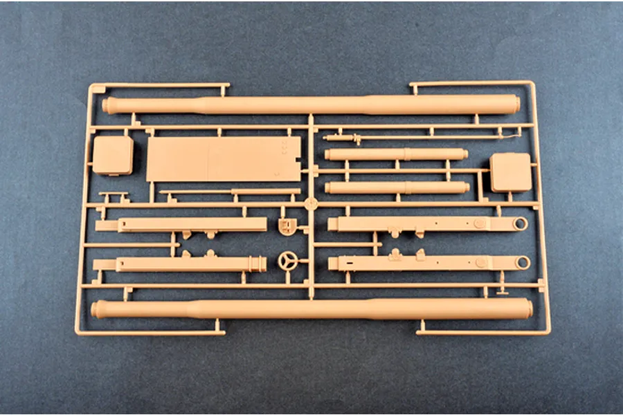 A plastic model kit sprue containing tan-colored parts for an M198 155mm towed howitzer, including long barrel sections and structural components.