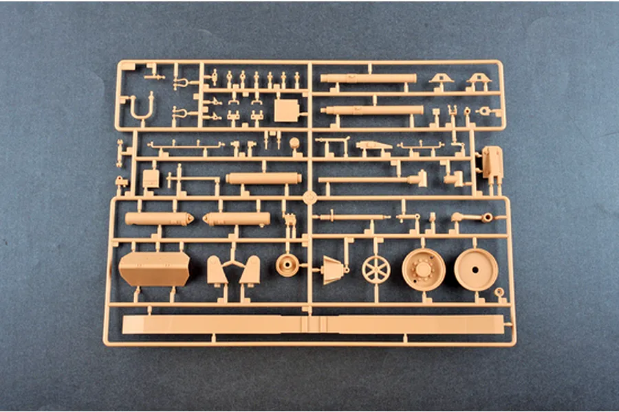 A tan plastic model kit sprue containing various parts for an M198 155mm towed howitzer on a dark grey background.