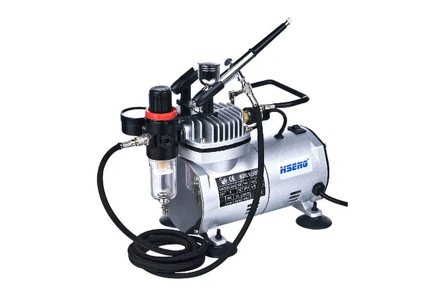 Hseng air compressor kit featuring a silver compressor unit with an attached airbrush, pressure regulator, and black braided hose.