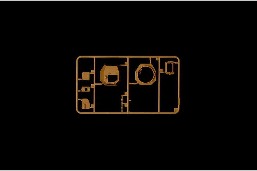 A tan plastic sprue containing various model tank parts, including a turret section, against a solid black background.