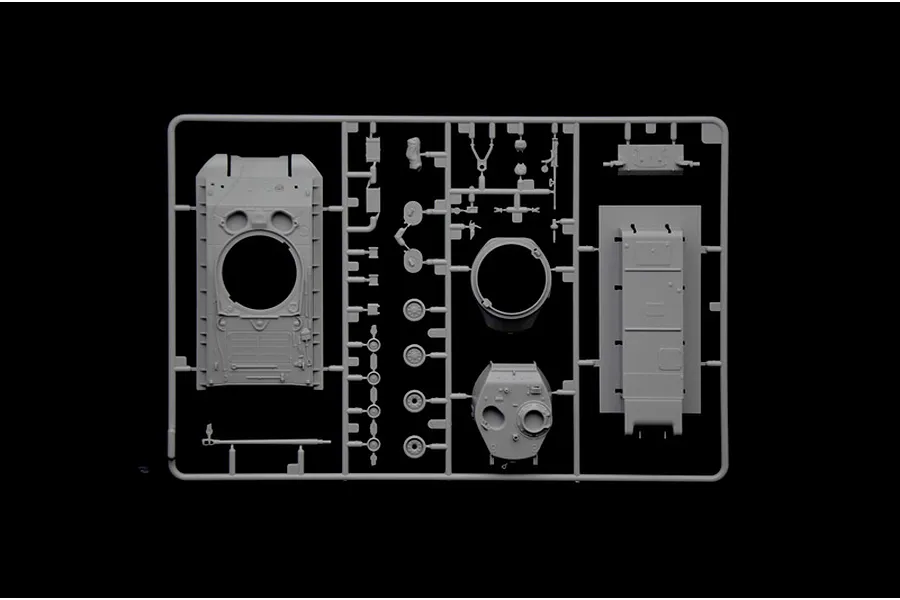 A grey plastic sprue containing various unpainted model tank parts, including the hull, turret, and small components, against a black background.