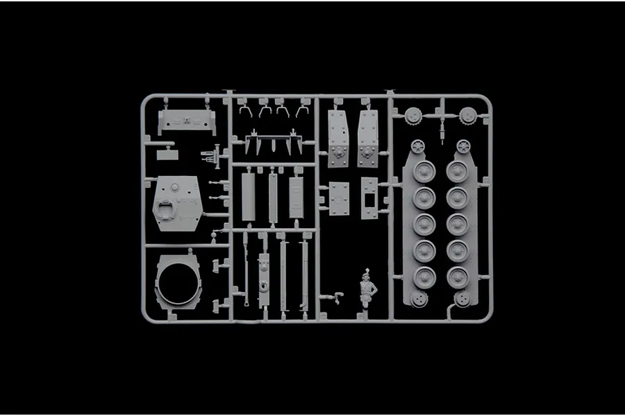 A grey plastic sprue containing various tank model parts, including road wheels, turret components, and a small figure, set against a black background.