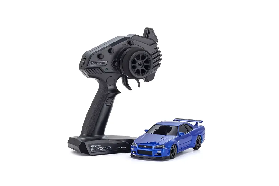 Kyosho Mini-Z Nissan Skyline GT-R R34 RC car in metallic blue next to a black Syncro KT-531P radio transmitter on a white background.