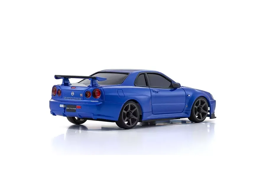 Rear three-quarter view of a metallic blue Kyosho Mini-Z Nissan Skyline GT-R R34 RC car on a white background.