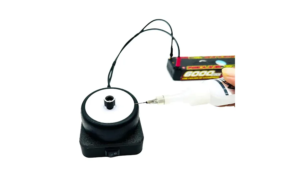 MTTR RC tire gluing tool powered by a LiPo battery, with a hand applying glue to the tire sidewall.