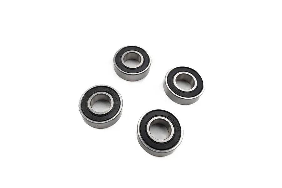 Four metal ball bearings with black rubber seals arranged on a white background.