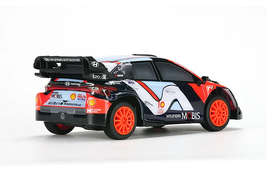 Rear three-quarter view of the Carisma Hyundai i20N Rally1 RC car featuring a blue, red, and white livery with orange wheels.