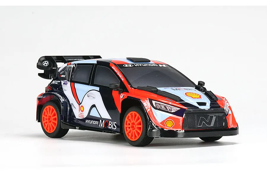 A 1/24 scale Carisma Hyundai i20N Rally1 RC car in Hyundai Motorsport livery with orange wheels, viewed from a front three-quarter angle against a white background.