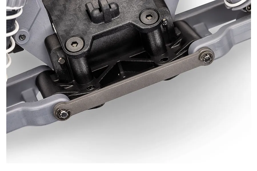 Close-up of the front suspension assembly on a Traxxas RC vehicle, showing the grey plastic control arms, black chassis components, and a metal tie bar.