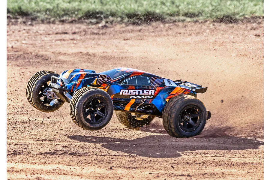 A Traxxas Rustler Brushless RC stadium truck driving on a dirt track, kicking up dust as it turns.