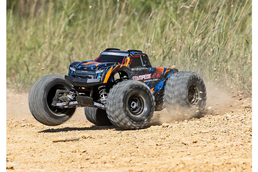 A Traxxas Stampede 4X4 VXL RC monster truck driving fast over a dirt track, kicking up dust with its large tires.