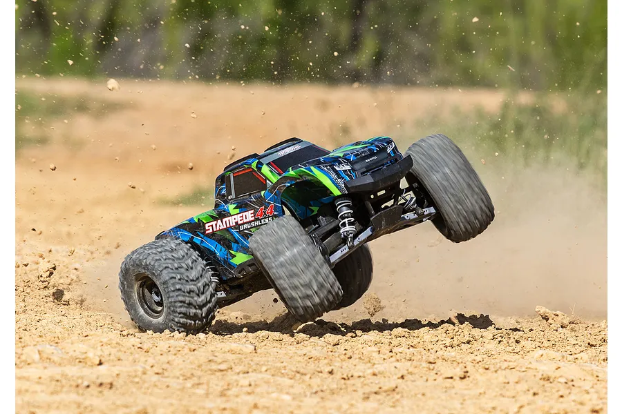 Traxxas Stampede 4X4 VXL RC monster truck performing a wheelie on a dirt track with dust kicking up.