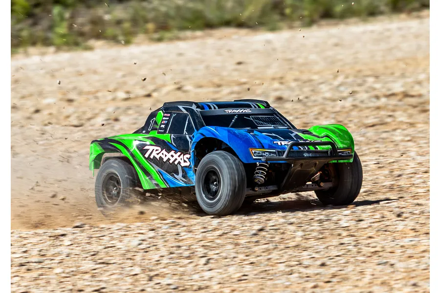 A Traxxas Slash 4X4 RC short course truck driving fast on a dirt track, kicking up dust and gravel.