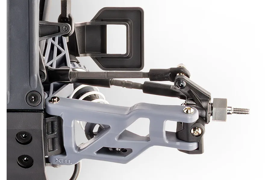 Close-up of the front suspension assembly on a Traxxas RC vehicle, showing the grey control arm, steering links, and wheel hex hub.